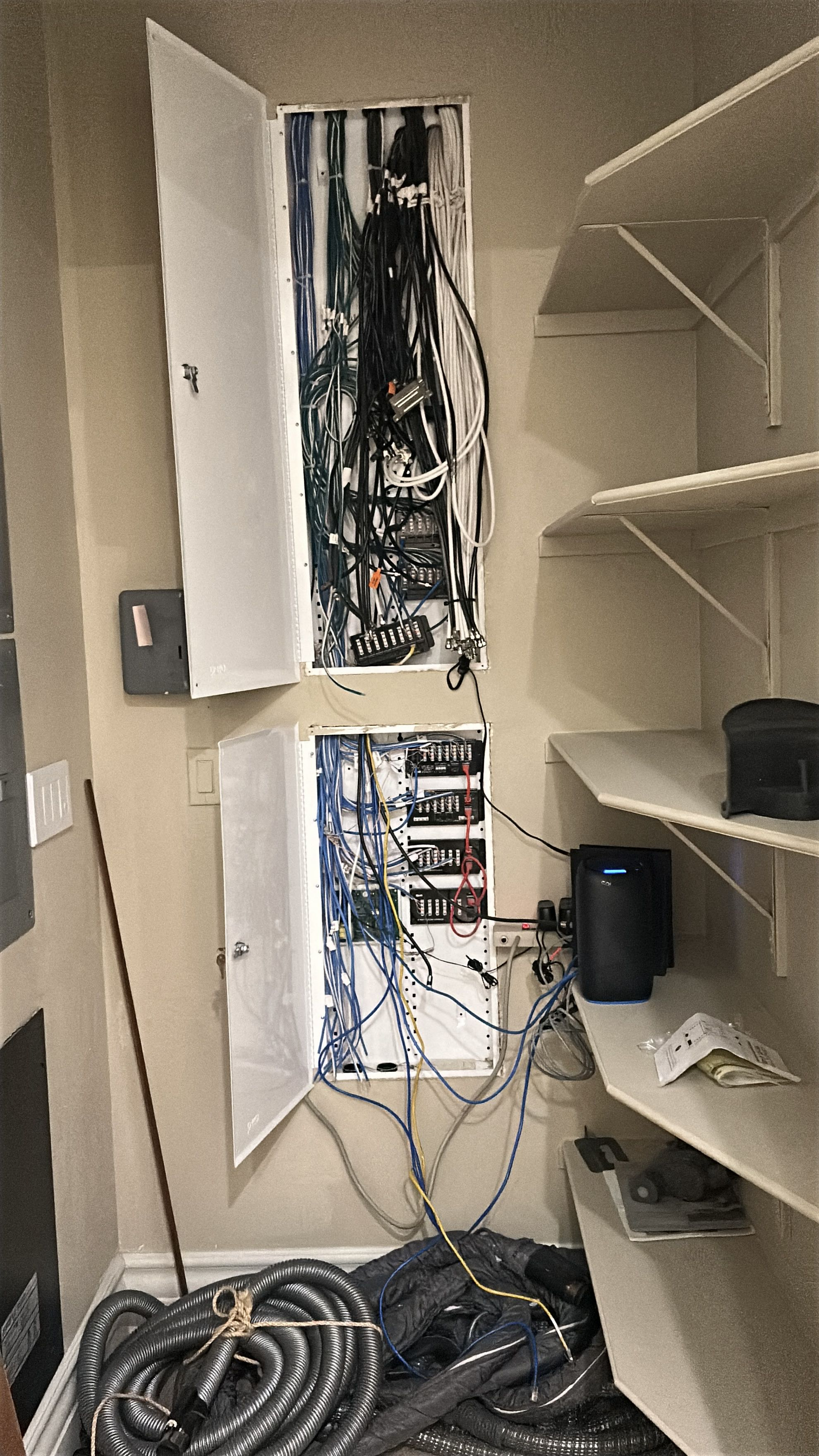 Cable management system with shelves and open panels showing network cables.